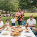 A diverse group of families celebrating Hispanic Heritage Month with traditional foods and cultural activities in a park.